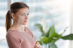 Pensive thoughtful young woman looking through window, arms cros