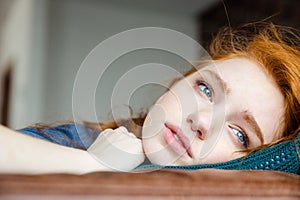 Pensive upset young woman lying on knitted pillow