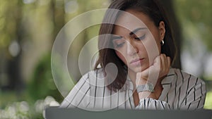 Pensive woman Brunette arabic Hispanic ethnic group sits at a table in a summer cafe with a laptop. Serious business