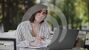 Pensive woman Brunette arabic Hispanic ethnic group sits at a table in a summer cafe with a laptop. Serious business