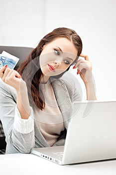 Pensive woman with computer and euro cash money