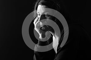 Pensive woman with downcast eyes on black photo