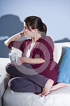 Pensive woman drinking coffee thinking on sofa