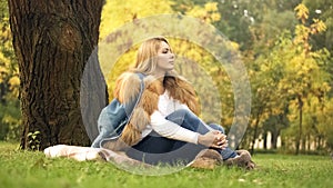 Pensive woman enjoying beautiful weather in autumn central park, yellow leaves