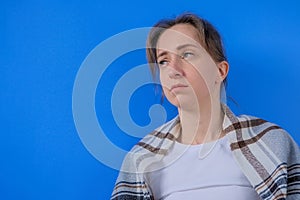 Pensive woman feeling sick, looking away against blue background at home