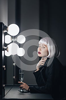 Pensive woman with glass of champagne thinking in dressing room