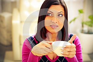 Pensive woman holding cup of coffee