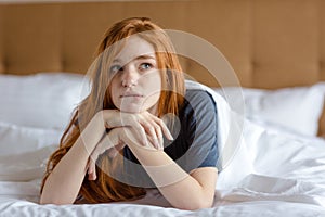 Pensive woman lying on the bed