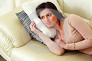 Pensive woman lying on the sofa