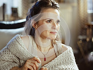 Pensive woman in modern living room in sunny autumn day