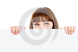 Pensive woman peeking over blank billboard