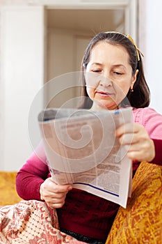 Pensive woman reading newspaper