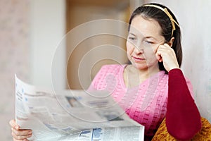 Pensive woman reading newspaper