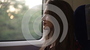 Pensive woman relaxing and looking out of a train window. Side view. Travel, transport concept