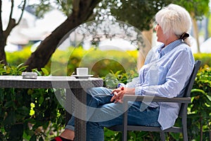 Pensive woman relaxing on an outdoor patio at a restaurant table