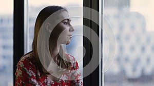 Pensive woman`s profile looking out of the window