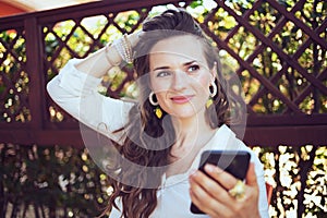 Pensive woman in shirt sending text message using smartphone