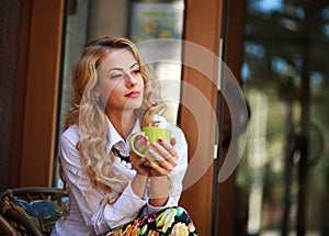 Pensive woman sitting with coffee cup and has a rest