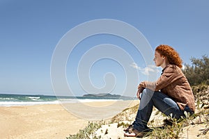 Pensive woman sitting on the dunes