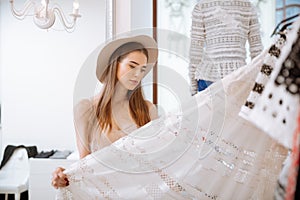 Pensive woman standing and choosing skirt in clothing store