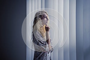 Pensive woman standing in front the window