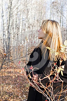 Pensive Woman in Stylish Black Coat Contemplating in Tranquil Autumn Woods, Serene Solitude