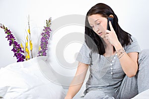 Pensive woman talk at phone on bed