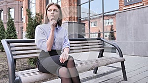 Pensive Woman Thinking and Sitting Ouside Office Building on Bench