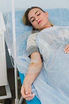 Pensive woman transfused lying in hospital ward