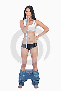 Pensive woman wearing jeans falling down because shes lost weigh