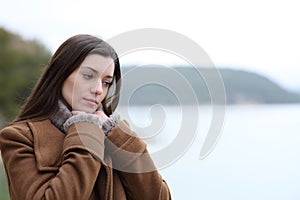 Pensive woman in winter thinking in a lake