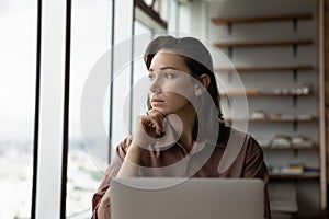 Pensive woman work on laptop look in distance thinking