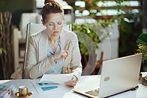 pensive woman worker in light business suit in green office