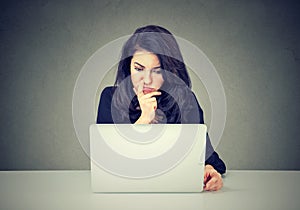 Pensive woman working on laptop computer