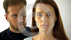 Pensive woman looking at camera man behind wife, inability to make own decisions photo