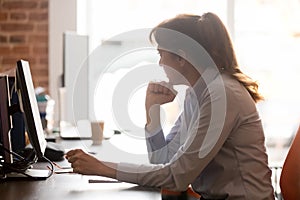 Thoughtful middle aged female employee sitting in workplace feels stressed