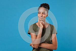 Pensive young african american woman girl in casual t-shirt posing isolated on blue background studio portrait. People