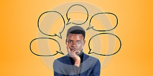 Pensive young African businessman and speech bubbles