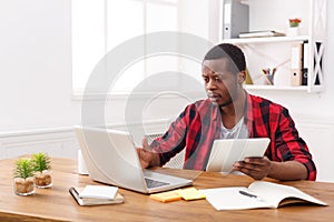 Pensive young black happy businessman in office, work with laptop