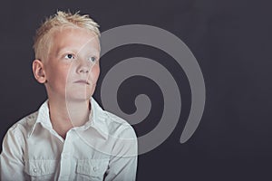 Pensive young boy looking upward over black