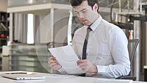 Pensive Young Businessman Reading Contract in Office