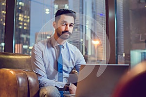 Pensive young businessman using laptop in a cafe.