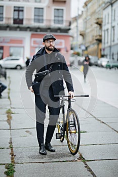 Pensive young businessman walking with bicycle on the city street