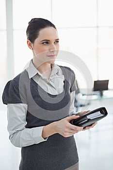 Pensive young businesswoman holding datebook