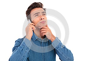 Pensive young casual man talking on the phone