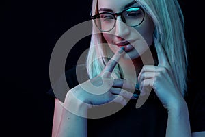 Pensive young Caucasian beautiful blonde woman with glasses . close-up portrait in neon light