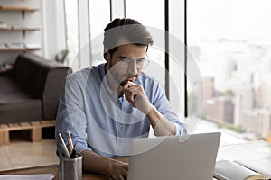 Pensive young Caucasian male employee work on computer