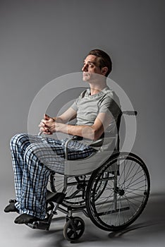 Pensive young disabled sitting in wheelchair