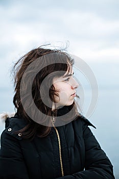 Pensive young girl looking to the sea from boat. Teenager girl at ferryboat. Cold grey sea