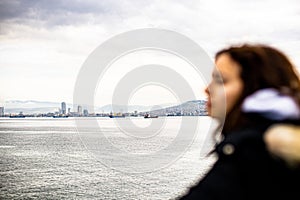 Pensive young girl looking to the sea from boat. Teenager girl at ferryboat. Cold grey sea